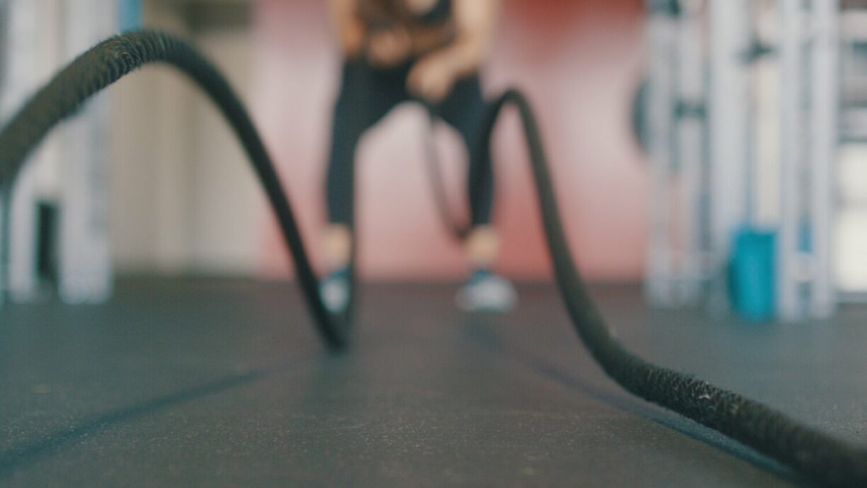 fitness person in gym exercises with battleropes