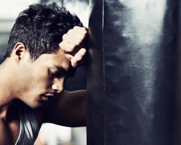 man rests head on boxing bag