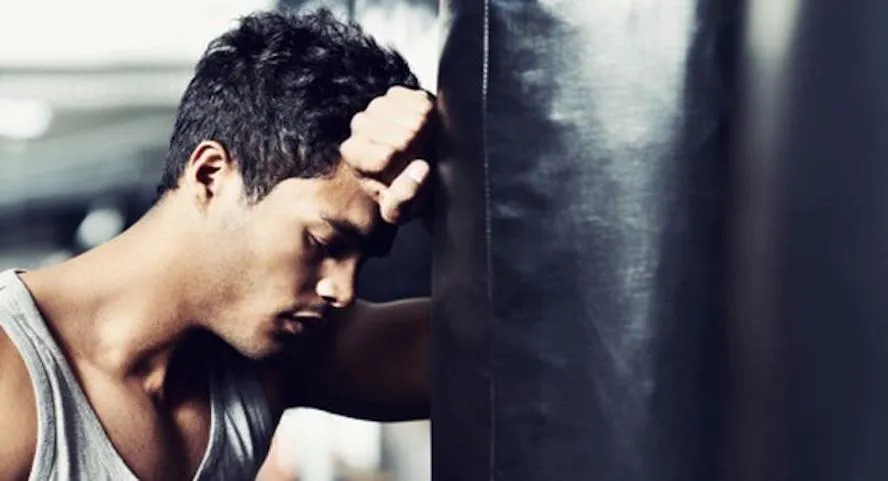 man rests head on boxing bag