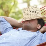 person sleeps in hammock with hat on face