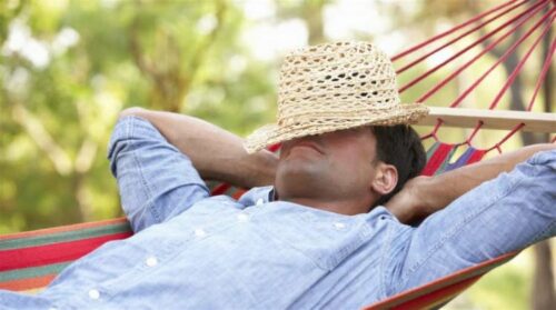 person sleeps in hammock with hat on face