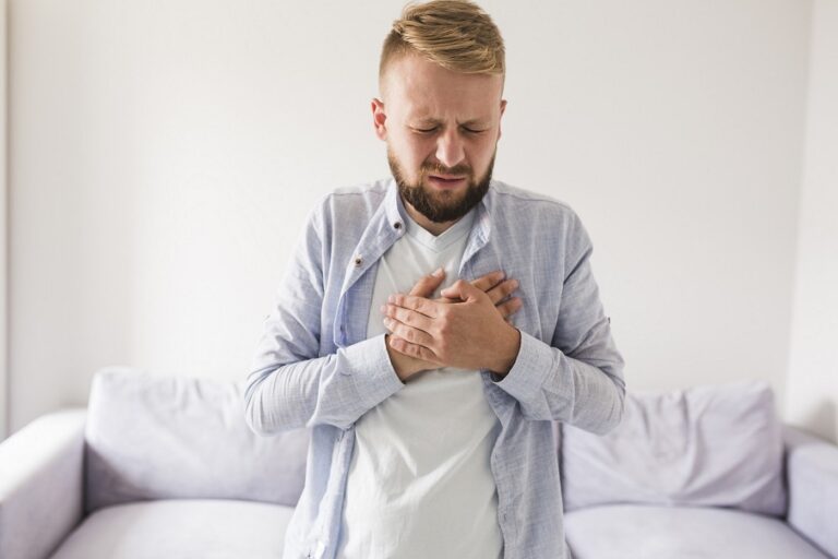 man holds hands across chest in pain