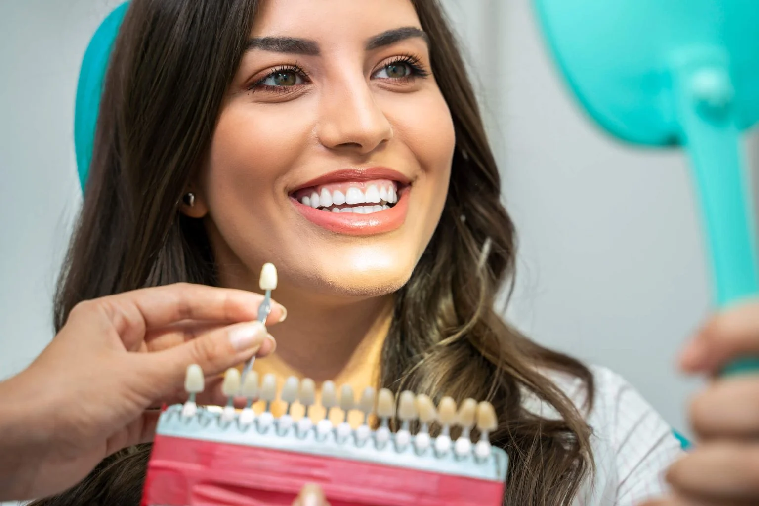 Woman compares teeth shades with dentist