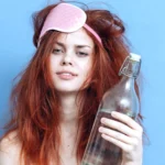 Woman with red hair bottle alcohol hangover sleep mask.