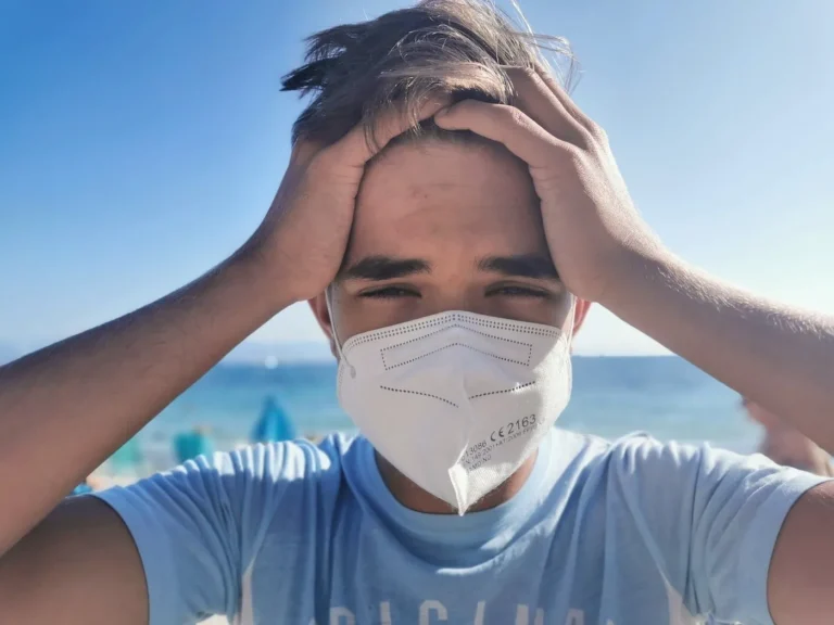 man holds head wearing facemask