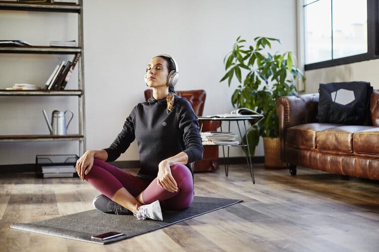 Woman sits cross legged on yoga mat