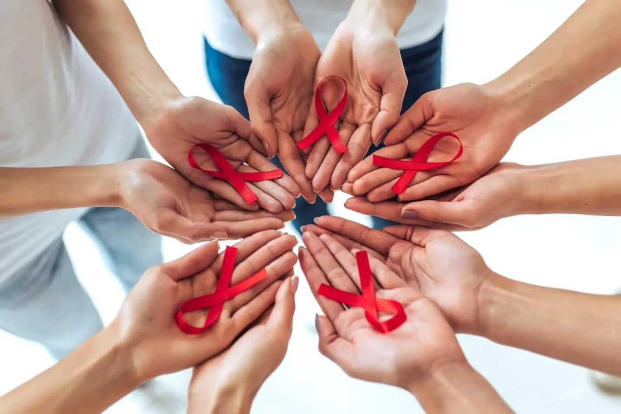 hands holding red ribbons for aids day