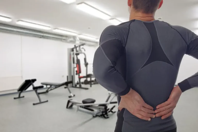 man stretches back after lifting too heavy in the gym