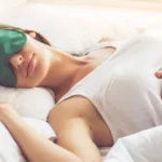Person sleeps with green eye mask on