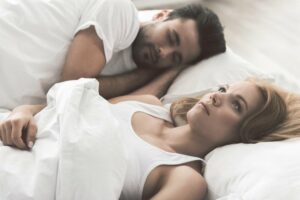 man sleeps whilst woman lays awake