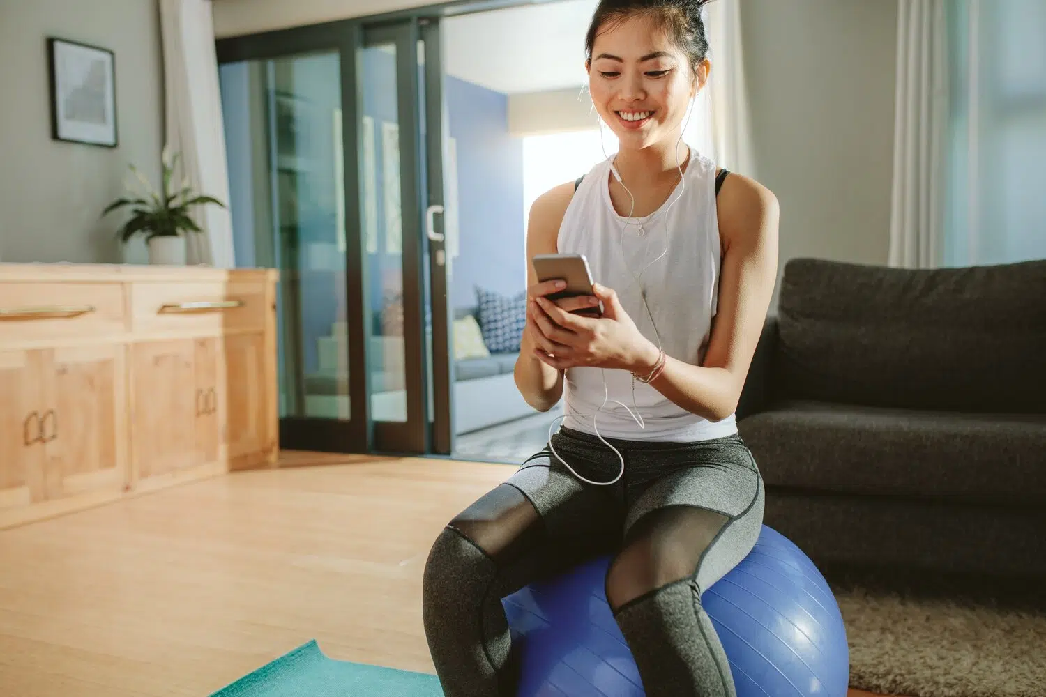 woman sits on ball with mobile phone