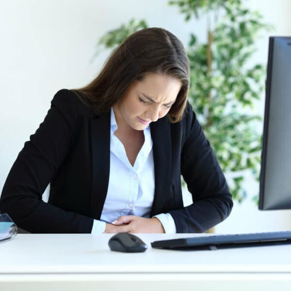 woman at desk holds stomach