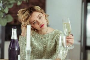 woman feeling sorry for herself with glass of alcohol