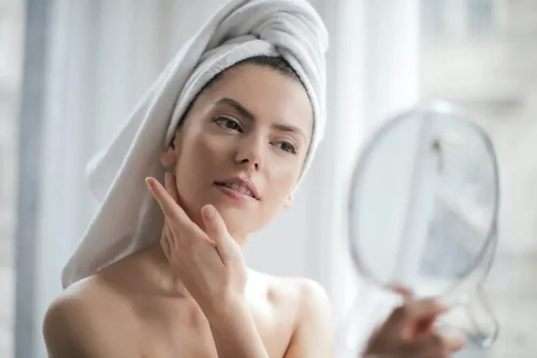 woman with towel on head looking in mirror