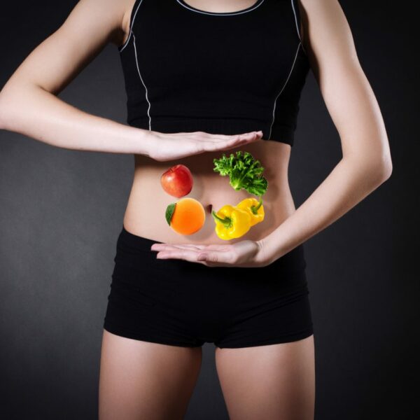 person in shorts and vest holds vegetables over stomach