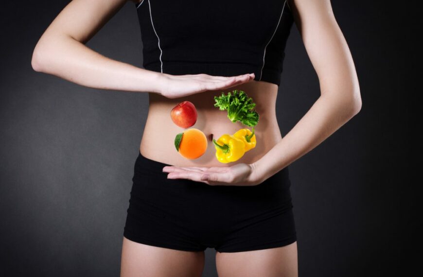 person in shorts and vest holds vegetables over stomach