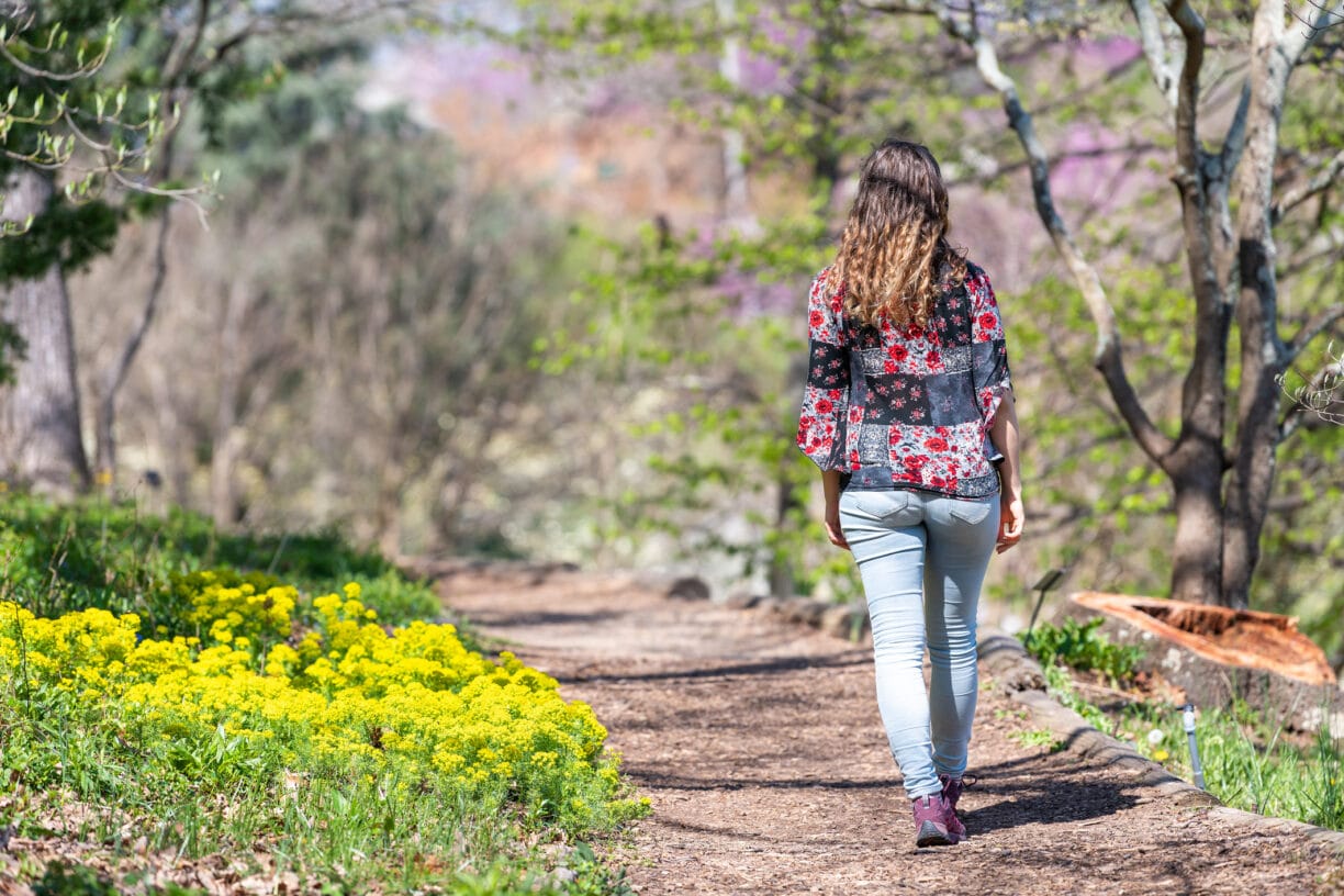 woman walks a path amongst trees