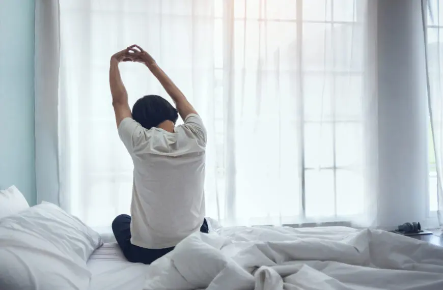 person stretches as they rise from bed e1612730636562