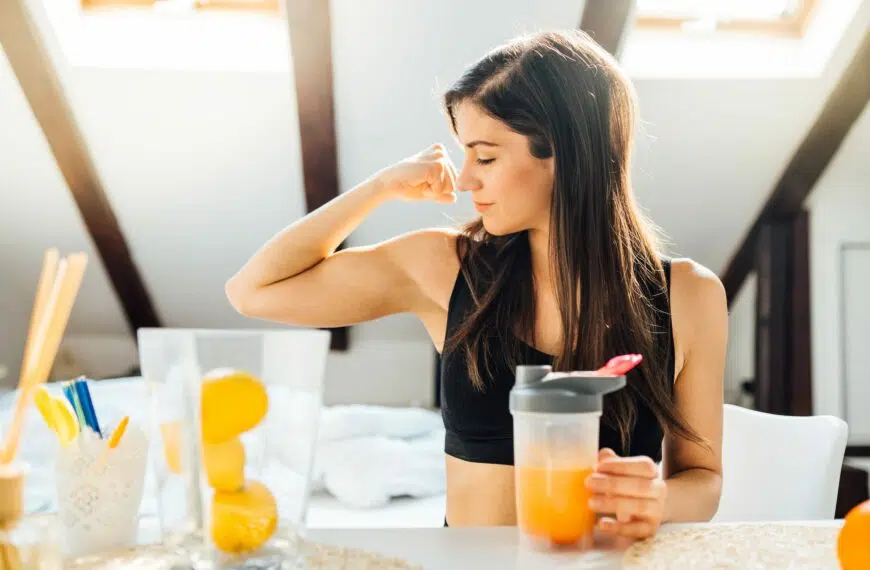 woman flexes muscles over orange juice