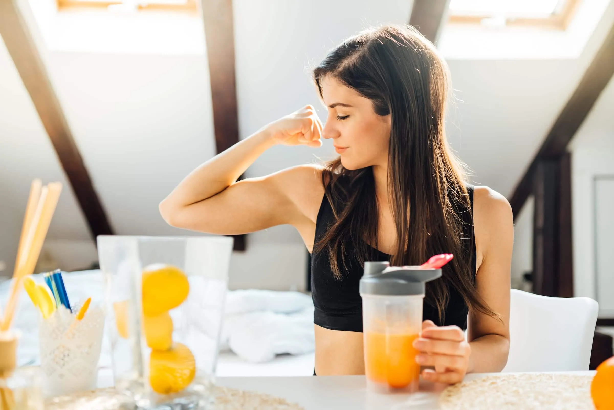 woman flexes muscles over orange juice