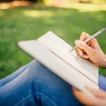 woman writing in journal outdoors