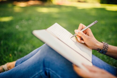 woman writing in journal outdoors