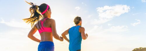 Fitness couple in bright clothing running on beach