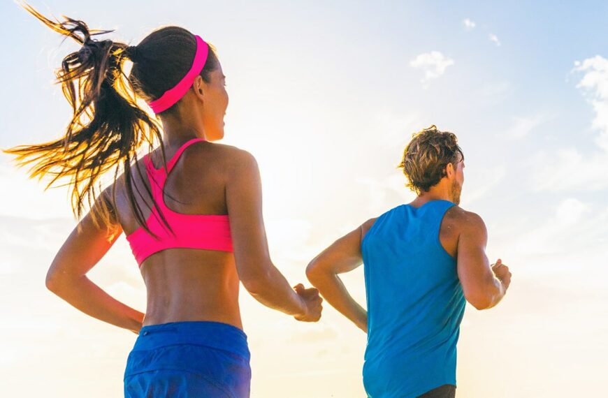 Fitness couple in bright clothing running on beach