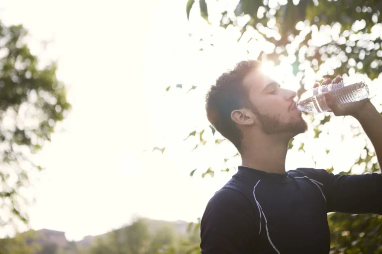 man drinks water from bottle outdoors scaled