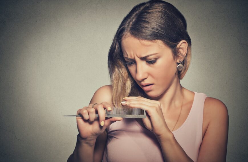 woman looks at hair in comb