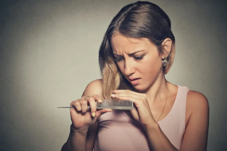 woman looks at hair in comb