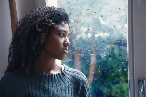 woman looks sad by rainy window scaled