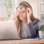 woman rubs eyes at screen