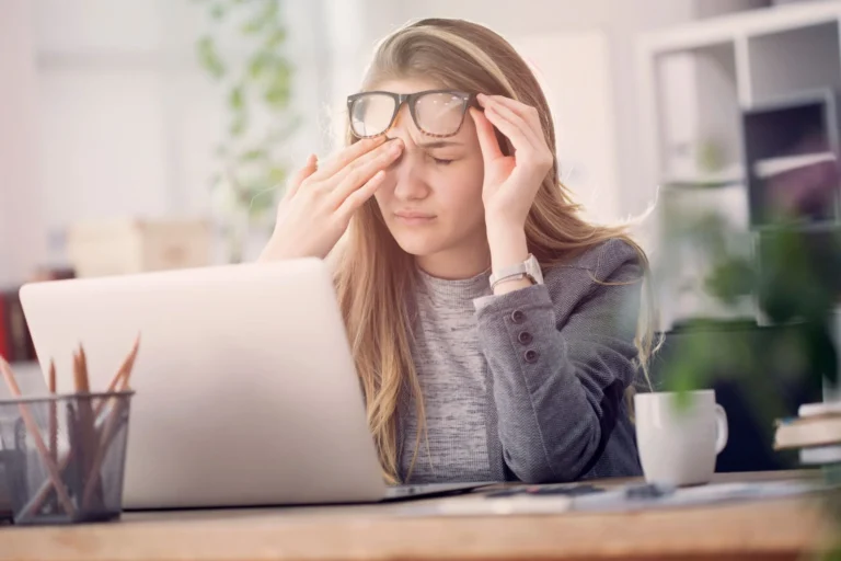 woman rubs eyes at screen