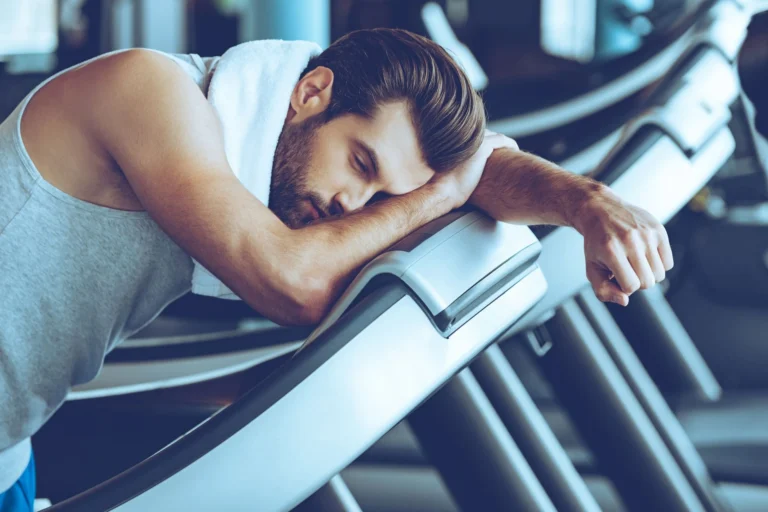 man leans over gym machinery scaled