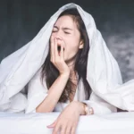 sleepy woman under covers