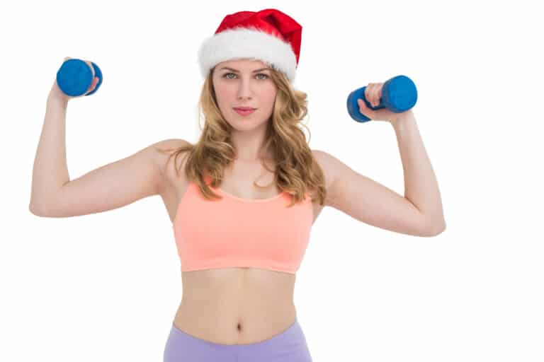 woman wears christmas hat and holds dummbells