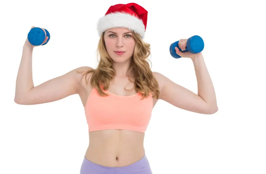 woman wears christmas hat and holds dummbells