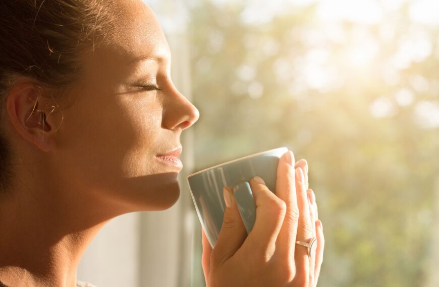 woman holding cup smiles in the sunshine