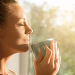 woman holding cup smiles in the sunshine