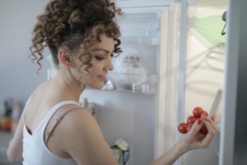 woman looking at tomatoes in fridge scaled