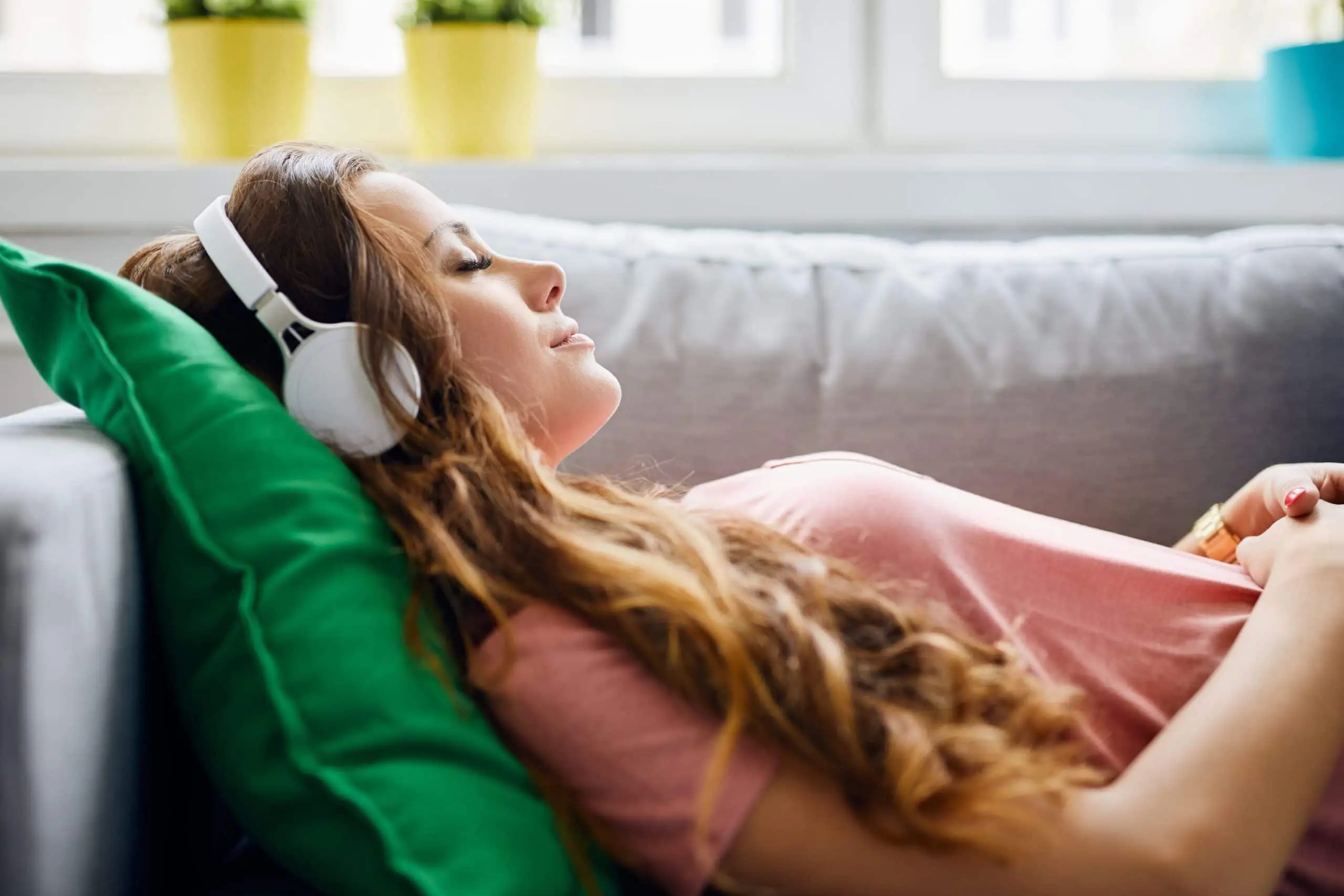 Woman relaxing on sofa wearing headphones scaled