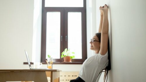 woman stretches back against a wall