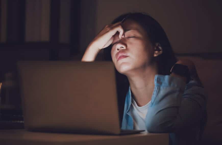 person with hand on head over laptop