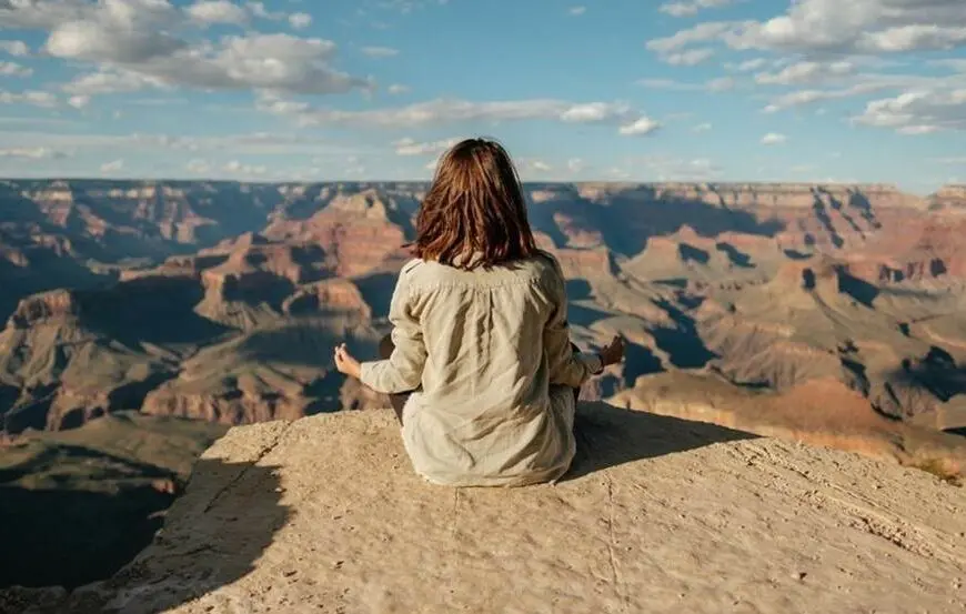 woman meditates on top of mountain