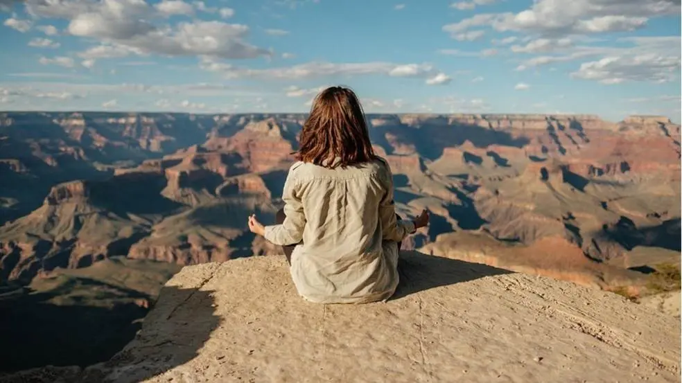 Woman meditates on top of mountain