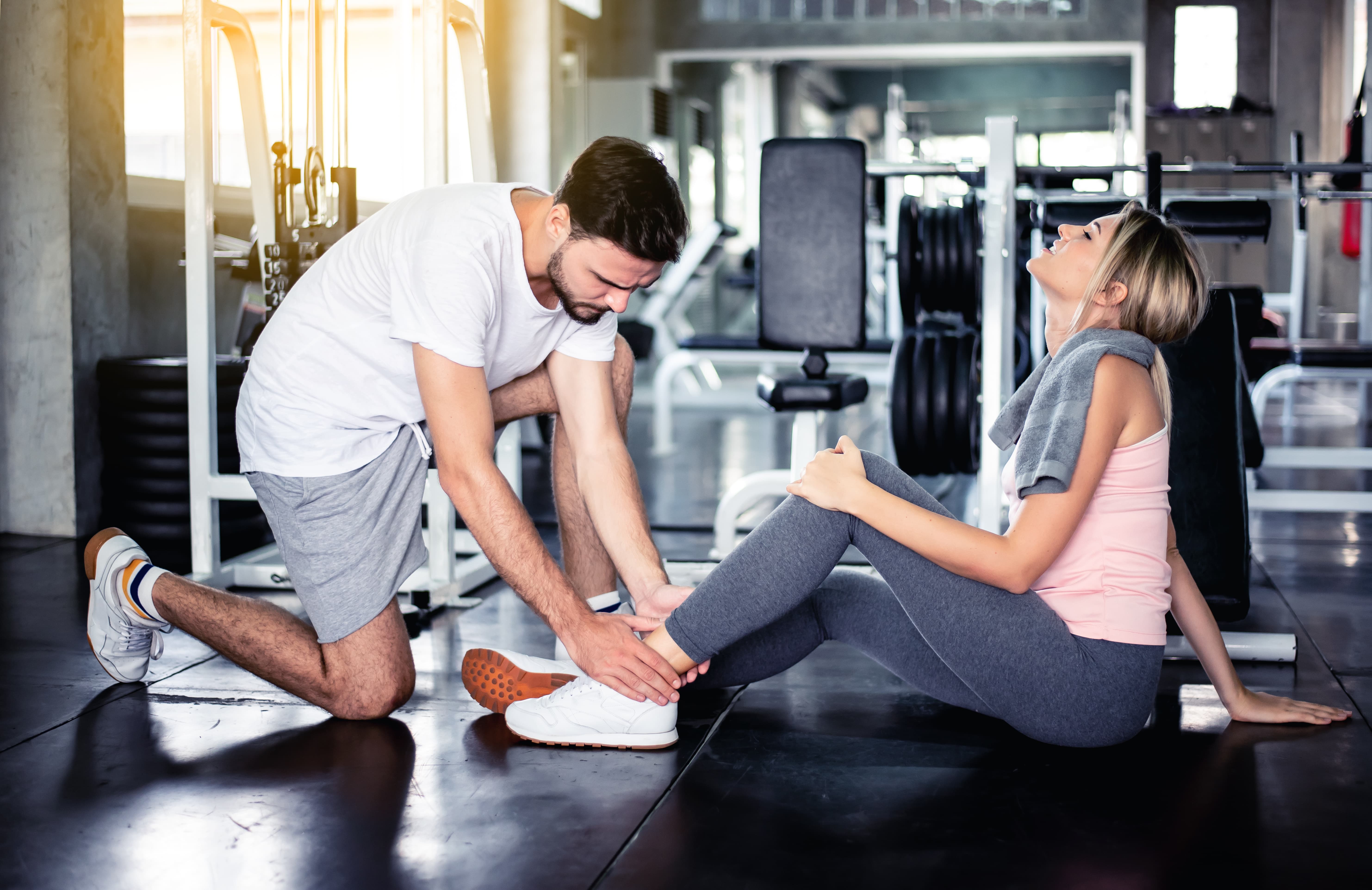 woman is looked after man following injury to leg in gym