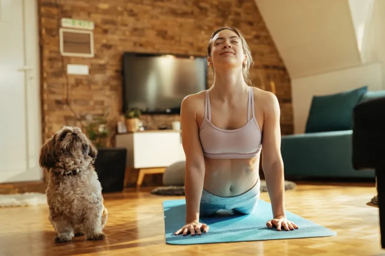 woman exerciese at home with dog watchcing on