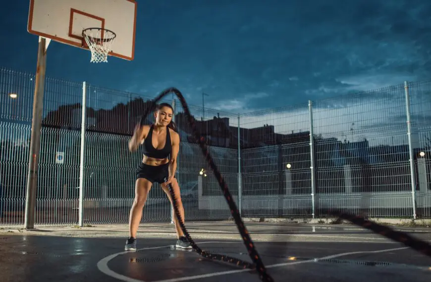 fit girl using battle ropes on basketball court scaled