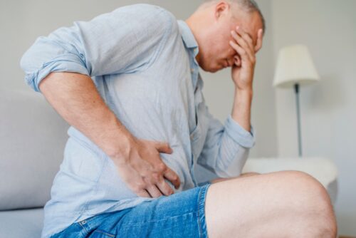 man holds side of stomach in pain